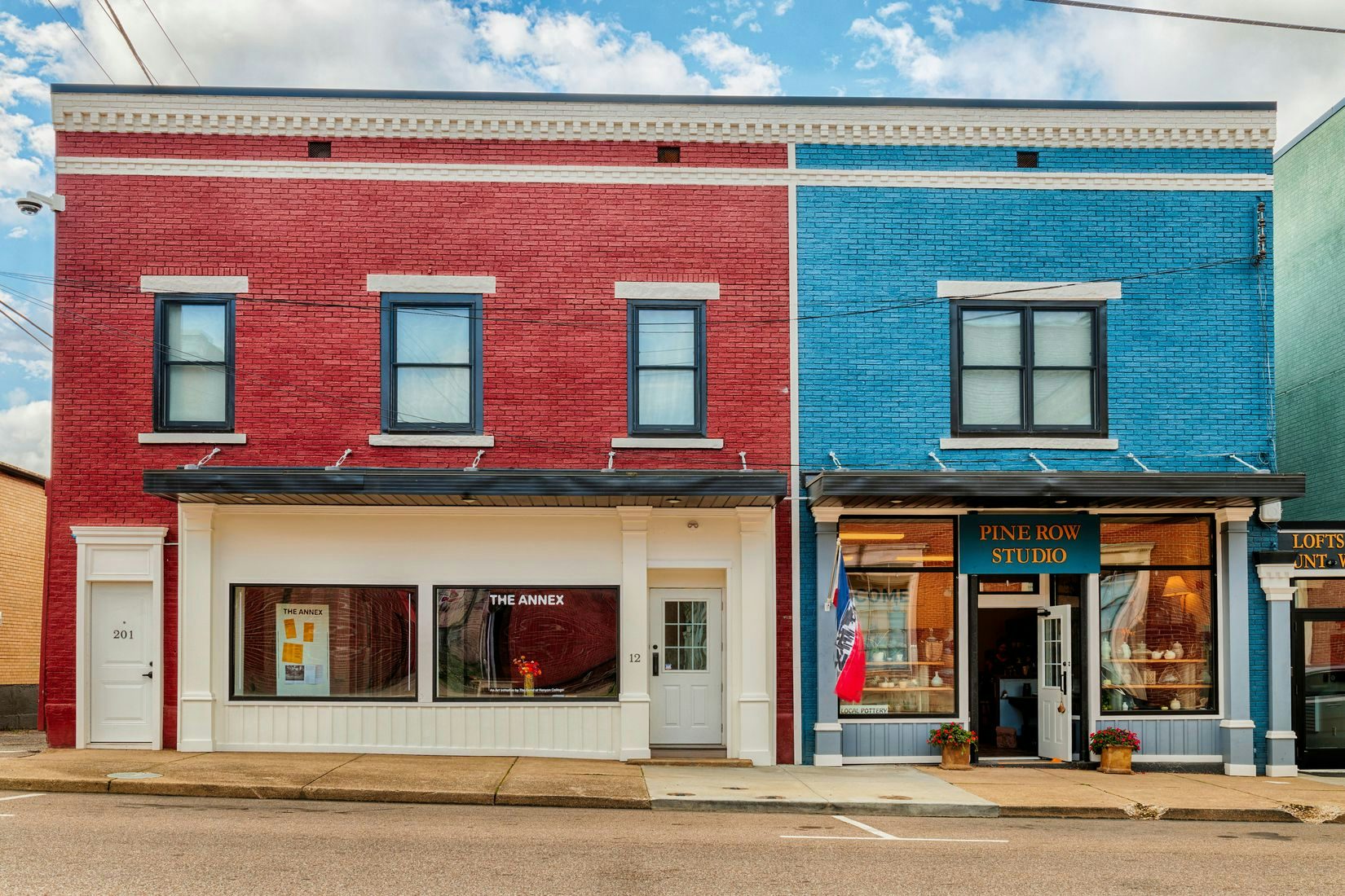 A frontal view of The Annex storefront in downtown Mount Vernon, OH. The building is brick red, but the storefront is painted eggshell. It is located next to a blue brick storefront. 